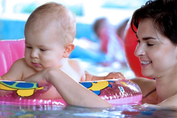 Baby and his mother are in a very intimate moment. They are taking a bath in the pool and playing together.